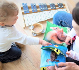 Woman reading with young children. Musical instruments nearby on the floor.